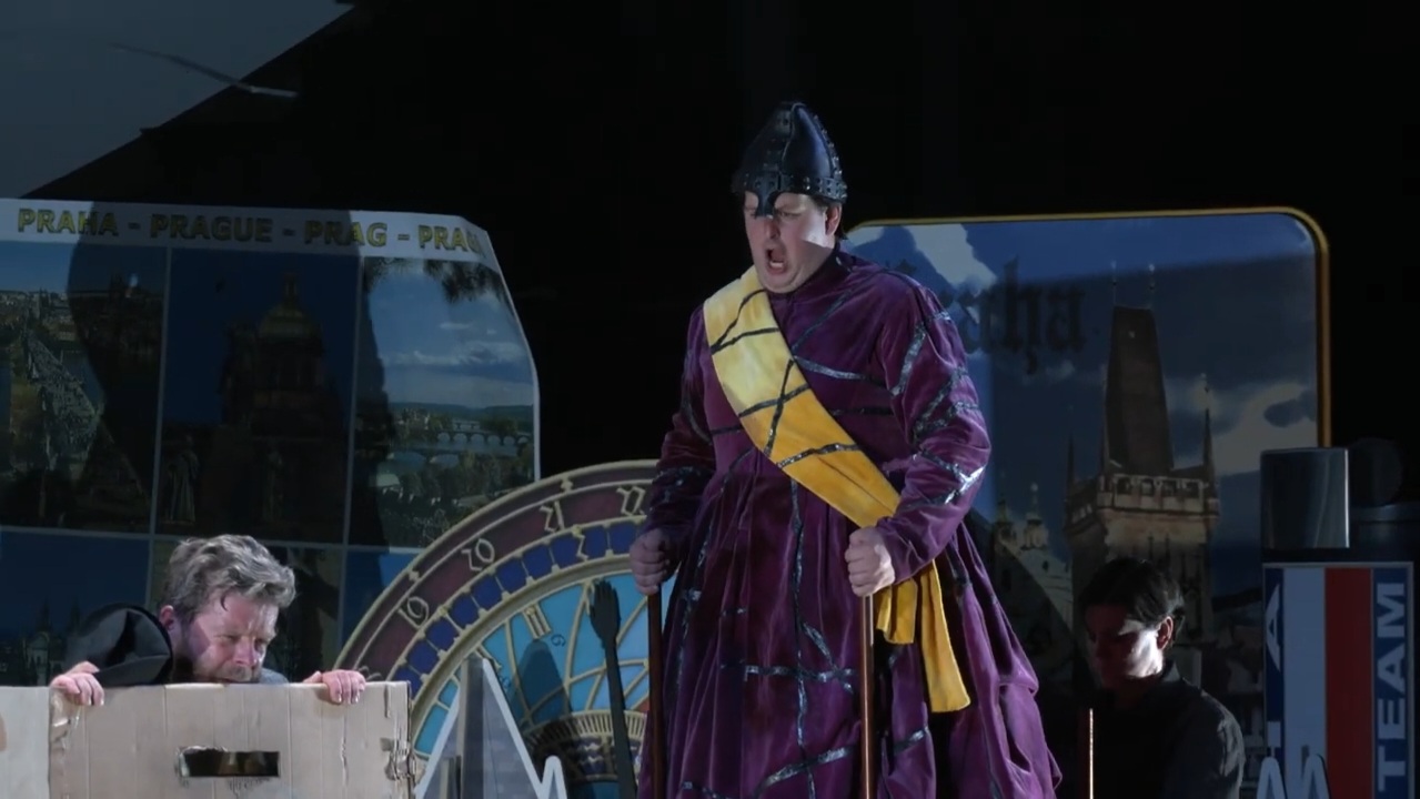 Colour photograph of Jonathan Forbes Kennedy, baritone, on stage as Vacek in The Excursions of Mr Brouček, Grange Park Opera, 2022 (photo credit: Grange Park Opera - still from video production by Stagecast)